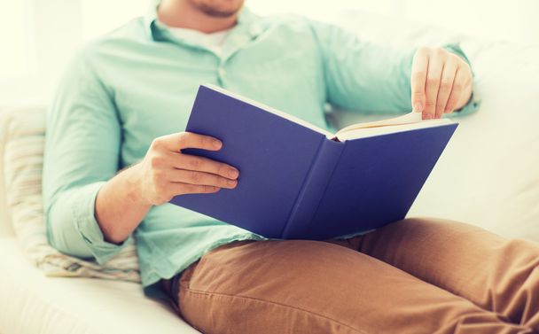 close up of man reading book at home - Foto, Imagen
