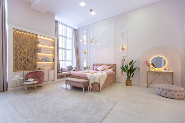 luxurious modern bedroom interior of an expensive spacious light stylish apartment. upholstered furniture and decorative lighting, soft pastel colors and cozy atmosphere - Foto, afbeelding