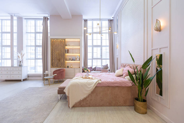 luxurious modern bedroom interior of an expensive spacious light stylish apartment. upholstered furniture and decorative lighting, soft pastel colors and cozy atmosphere - Φωτογραφία, εικόνα