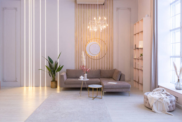 luxurious modern interior of the living room of an expensive spacious bright apartment. upholstered furniture and decorative lighting, soft pastel colors and cozy atmosphere - Valokuva, kuva
