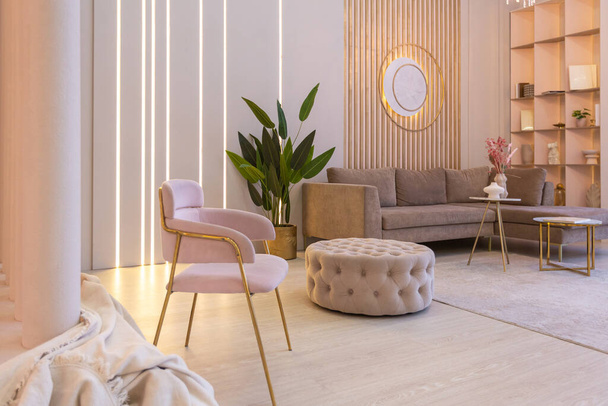 luxurious modern interior of the living room of an expensive spacious bright apartment. upholstered furniture and decorative lighting, soft pastel colors and cozy atmosphere - Photo, image