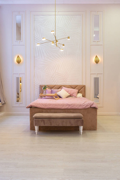 luxurious modern bedroom interior of an expensive spacious light stylish apartment. upholstered furniture and decorative lighting, soft pastel colors and cozy atmosphere - Fotoğraf, Görsel