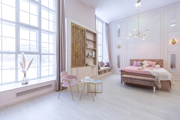 luxurious modern bedroom interior of an expensive spacious light stylish apartment. upholstered furniture and decorative lighting, soft pastel colors and cozy atmosphere - Fotografie, Obrázek