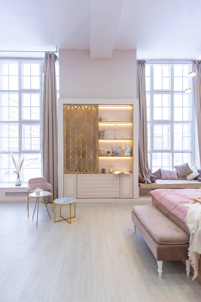 luxurious modern bedroom interior of an expensive spacious light stylish apartment. upholstered furniture and decorative lighting, soft pastel colors and cozy atmosphere - Foto, afbeelding