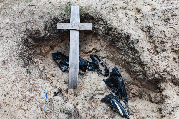 Σταυροί εμφανίζονται σε ένα δασικό τάφο μετά από εκταφή στην πόλη του Ιζίου, πρόσφατα απελευθερωθεί από τις ουκρανικές δυνάμεις, στην περιοχή Χάρκοβο, Ουκρανία. - Φωτογραφία, εικόνα