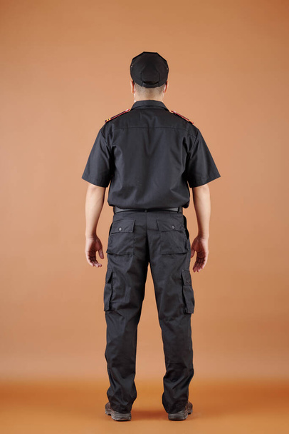 Confident security guard in black uniform, view from the back - Foto, immagini
