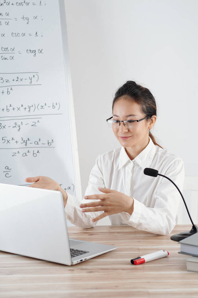 Smiling math tutor explaining difficult topic to student during online class - 写真・画像