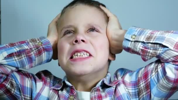 Las emociones del niño. Un niño de 6-7 años sostiene la cabeza y representa la ira, el horror, el miedo, los gritos - Metraje, vídeo