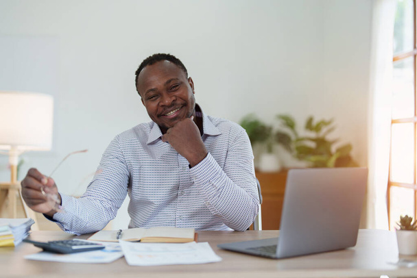 Мужчина среднего возраста американский африканский бизнесмен держит ноутбук с поднятыми руками в победитель жеста, Счастлив быть успешным празднуя успех достижения. - Фото, изображение
