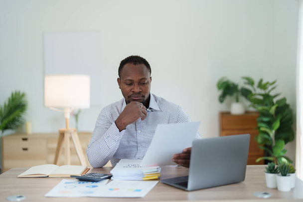 middle aged man American African using computer laptop with planning working on financial document, tax, exchange, accounting and Financial advisor. - 写真・画像