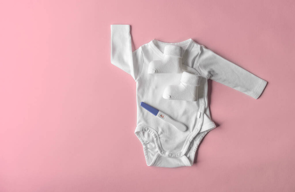 Positive pregnancy test on the background of childrens clothing. There is space for text. - Fotoğraf, Görsel