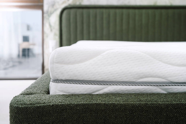 wybiórczy nacisk na nowy materac z pianki ortopedycznej z białą bawełnianą pokrywą na nowoczesnym łóżku w domu, komfortowa koncepcja spania, widok z przodu - Zdjęcie, obraz