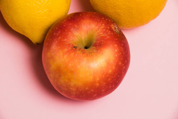 Omena ja sitruunat vaaleanpunainen tausta lähikuva. Herkullisia hedelmiä kirkkaalla taustalla - Valokuva, kuva