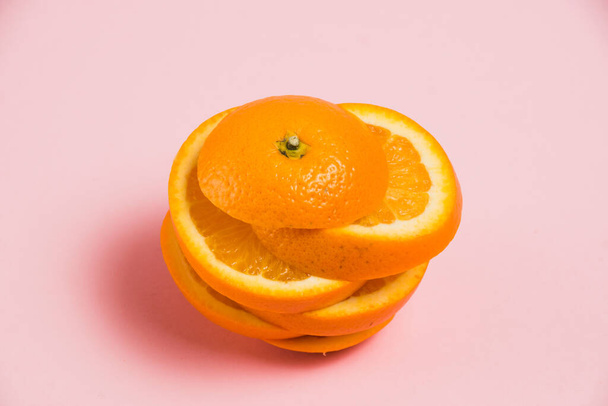 Pokrojona soczysta pomarańcza na różowym tle. Pyszne owoce na jasnym tle - Zdjęcie, obraz