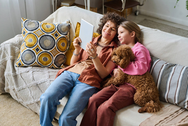 Vista ad alto angolo della famiglia di due persone che trascorrono il loro tempo libero a casa insieme al cane utilizzando tablet digitale - Foto, immagini