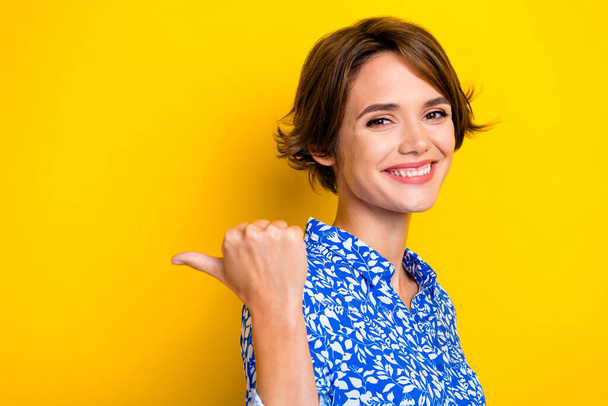 Photo of cute pretty woman dressed blue blouse pointing thumb back empty space isolated yellow color background. - Фото, зображення