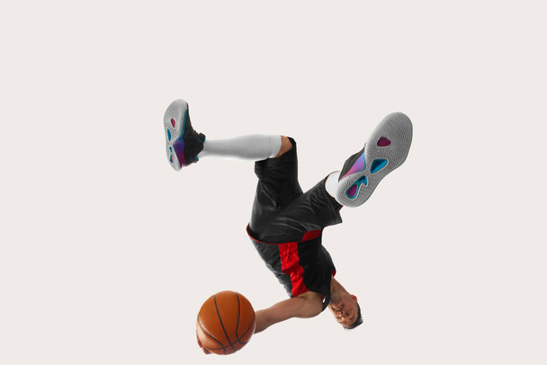 Development of movements. Image of professional basketball player in sports uniform with ball in motion, action over white studio background. Motion, action, sport concept - Photo, Image