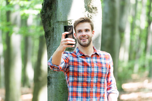 man blogger take selfie outdoor. man blogger take selfie on phone. man blogger take selfie on smartphone. photo of man blogger take selfie in the forest. - Φωτογραφία, εικόνα