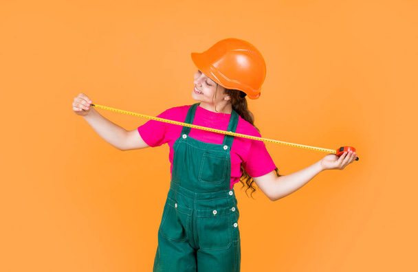 Smart professional. building and construction. concept of repair. Little girl use measuring tape. engineer. happy child hold tape measure. kid builder wear helmet. teen girl in hard hat and uniform. - Fotó, kép