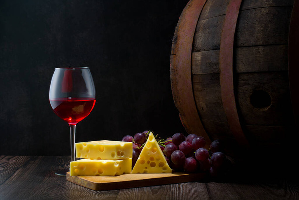Red wine in low light with cheese and grape,wine barrel and glass,still life - 写真・画像