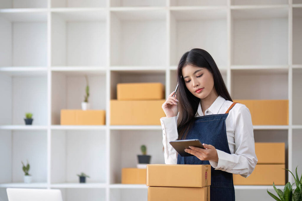 Startup small business entrepreneur SME, asian woman packing cloth in box. Portrait young Asian small business owner home office, online sell marketing delivery, SME e-commerce telemarketing concept - 写真・画像