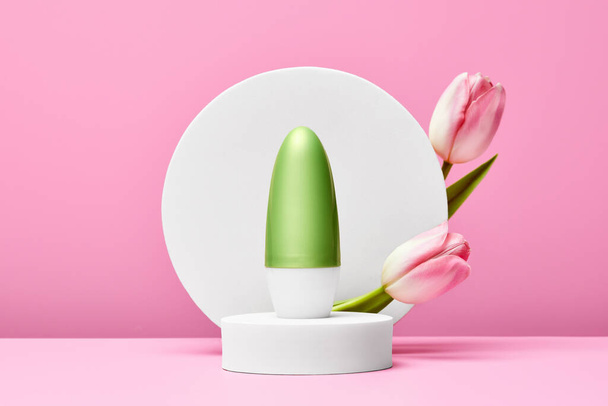 Deodorant on white round podium with pastel tulips on pink background. minimal scene - Photo, image