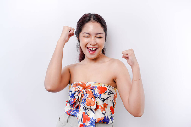 A young Asian woman with a happy successful expression wearing floral top isolated by white background - 写真・画像