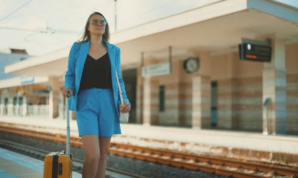 Woman with travel suitcase is waiting for a train. - Φωτογραφία, εικόνα