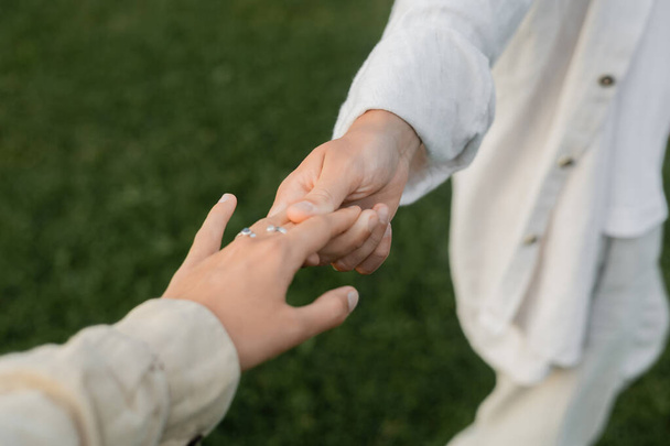 vue partielle de yoga homme en lin blanc vêtements tenant la main de la jeune femme à l'extérieur - Photo, image