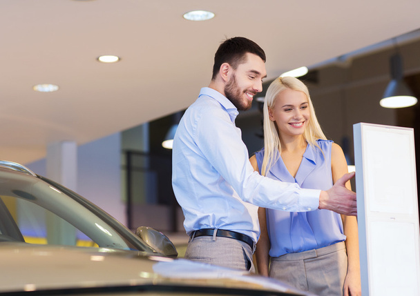 happy couple buying car in auto show or salon - Foto, Imagen