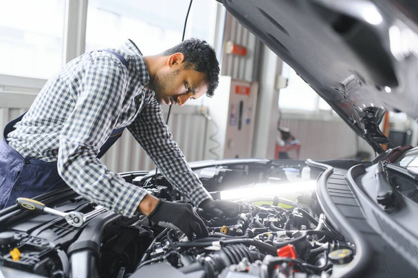 service, repair and profession concept - indian mechanic at car service. - Фото, изображение