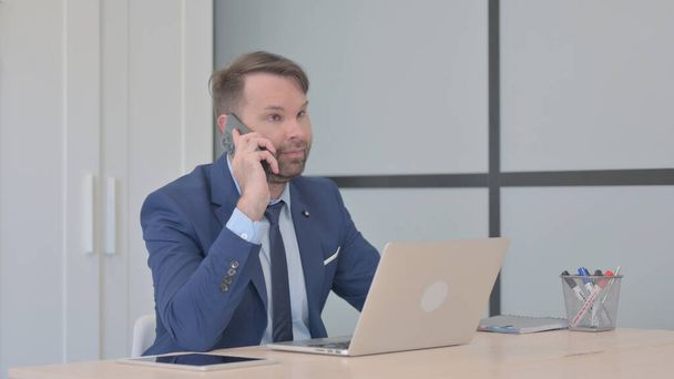 Homme d'affaires parlant au téléphone au travail - Photo, image