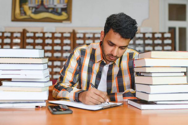 Male indian student at the library with book. - Fotoğraf, Görsel