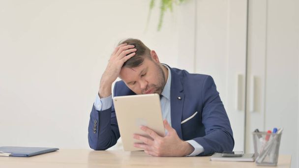 Businessman Upset by Loss on Tablet - 写真・画像