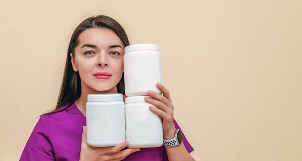 Woman cosmetologist holds in her hands white jars for cosmetic products - Valokuva, kuva