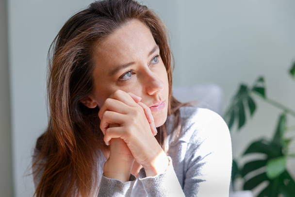 Stressed young woman looking away at window sitting on couch at hom - Photo, image