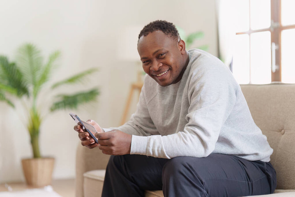A fiatal afro-amerikai férfi, aki mobiltelefont használ, bankkártyával rendelkezik. banki alkalmazás, online vásárlási koncepció. - Fotó, kép