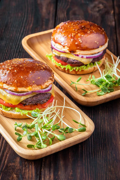 Two glazed burgers on the wooden background - Фото, изображение