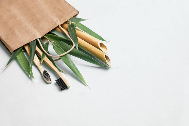 Spazzolino di bambù e borsa ecologica su un tavolo con spazio per copiare su uno sfondo bianco. Composizione in stile di posa piatta con foglie di bambù - Foto, immagini