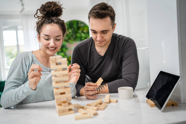woman and man happy caucasian couple husband and wife or friends playing jenga table game at home having fun happy smile leisure time spending time together family time copy space real people - Фото, зображення