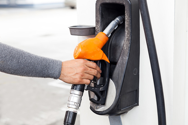 Closeup of woker hand holding gas pump nozzle at gas station. - Foto, Bild