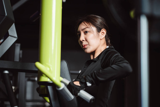 Women working out with weights training machine exercise lifting dumbbells at fitness gym. Fitness muscular body weight loss. Bodybuilding healthy lifestyle. - 写真・画像