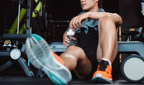 Man exercise workout in gym fitness breaking and resting after training sport with dumbbells and water bottle healthy lifestyle bodybuilding. - 写真・画像