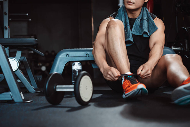Man exercise workout in gym fitness breaking and resting after training sport with dumbbells and water bottle healthy lifestyle bodybuilding. - 写真・画像