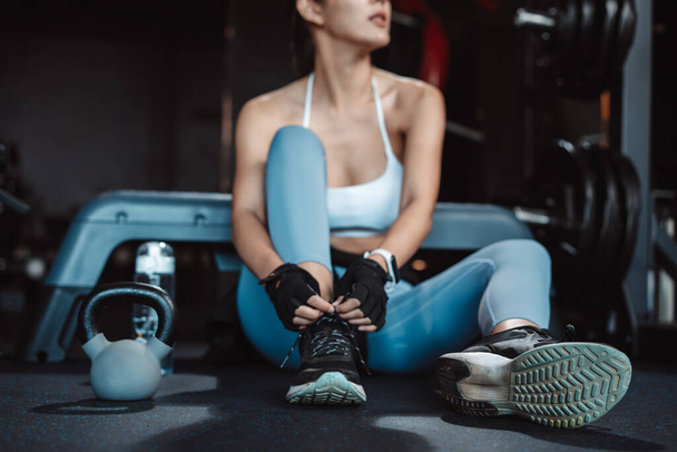 Woman exercise workout in gym fitness breaking relax after training sport with kettlebell, dumbbells and water bottle healthy lifestyle bodybuilding. - Photo, Image