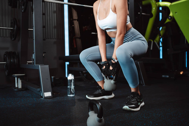 Woman exercise workout at gym fitness training sport with kettlebell weight lifting and legs squat healthy lifestyle bodybuilding. - Photo, Image