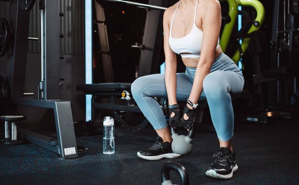 Woman exercise workout at gym fitness training sport with kettlebell weight lifting and legs squat healthy lifestyle bodybuilding. - 写真・画像