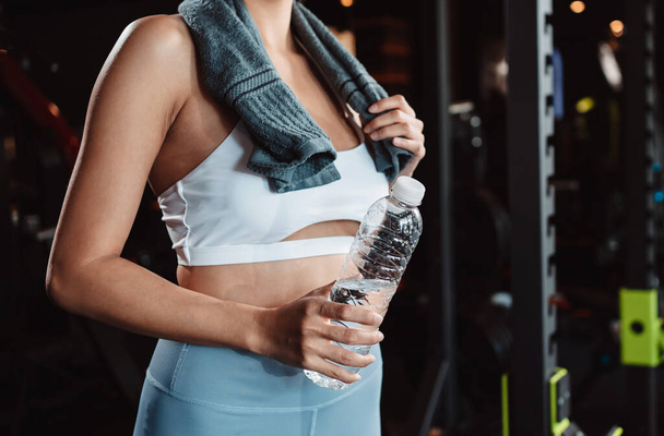 Woman drinking water recovery health exercise workout in gym fitness breaking relax after training sport with kettlebell, dumbbells and water bottle healthy lifestyle bodybuilding. - 写真・画像