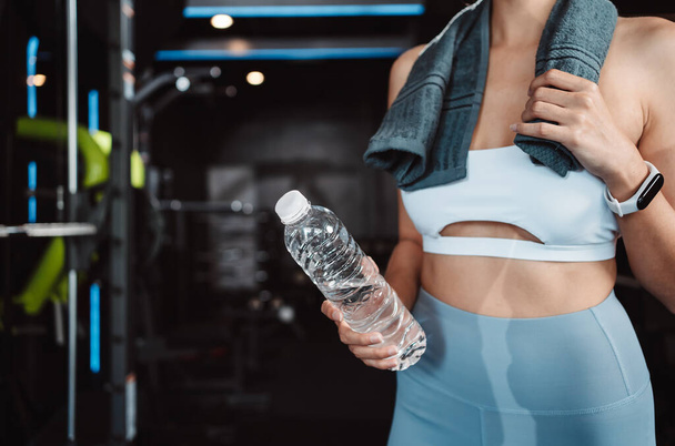 Woman drinking water recovery health exercise workout in gym fitness breaking relax after training sport with kettlebell, dumbbells and water bottle healthy lifestyle bodybuilding. - Zdjęcie, obraz