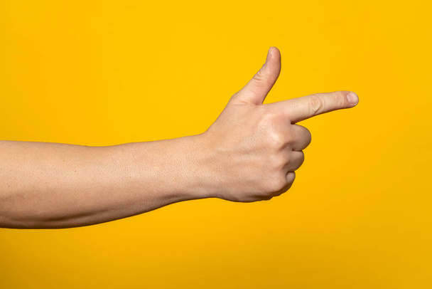 Mans hand making shooting, gesture. Hand gun gesture on isolated yellow background. Mans hand pointing a finger - Fotoğraf, Görsel